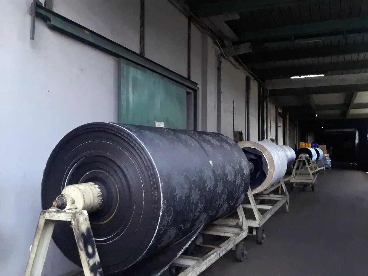 Large industrial rolls of patterned chenille carpets in a textile factory, showcasing Sakakriya's bespoke manufacturing and OEM solutions for global brands