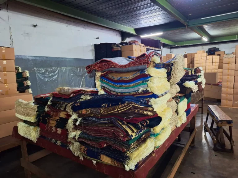 Stacks of finished premium chenille prayer rugs and packaged boxes in the Sakakriya.id warehouse, ready for international wholesale shipment